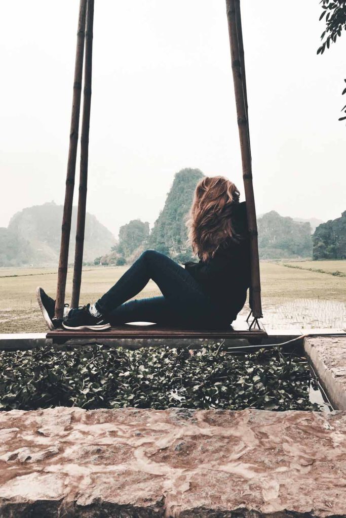 girl sitting on a swing in front of a panoramic mountain view