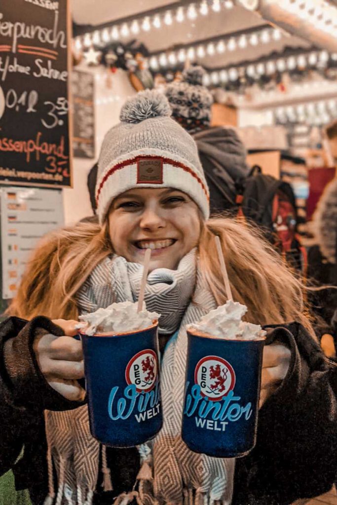 A girl holding two cups with hot chocolate and cream at the Christmas Market at Königsallee