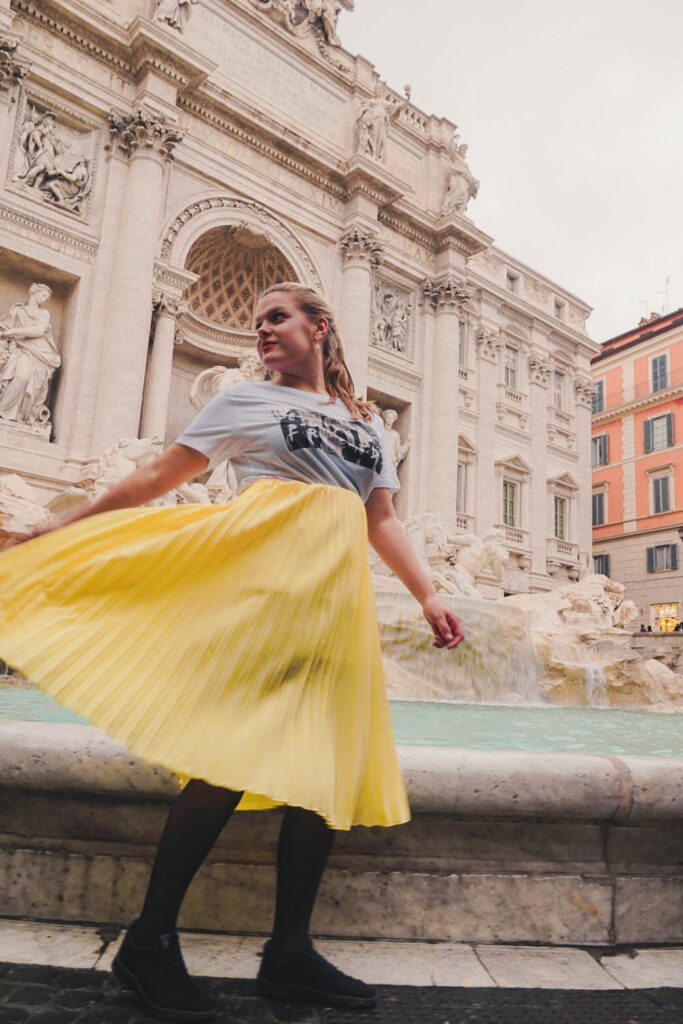 girl with yellow skirt in front of Trevi Fountain