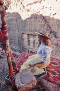 Girl, sitting on an edge, watching above the Treasury of Petra
