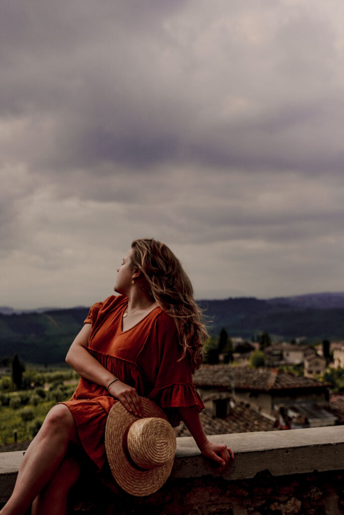 Woman in an orange dress watching over the scenic landscape of Tuscany in San Gimignano