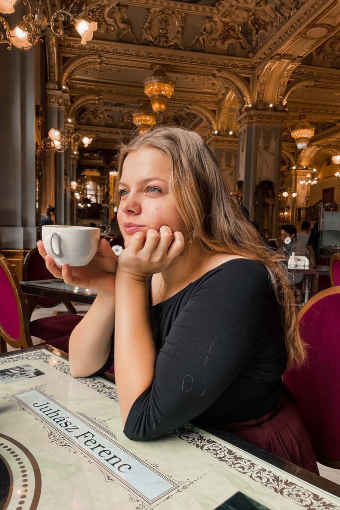 Paula from La Vie En Marine drinking a cup of coffee in the New York Café in Budappest. 